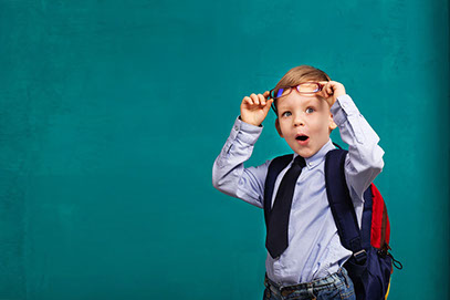 Boy with glasses and backpack looking surprised