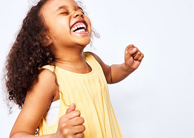 Girl smiling big with yellow dress on