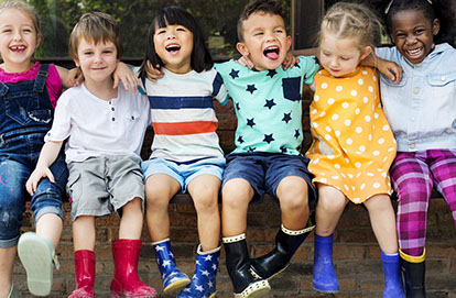 Group of diverse children smiling with arms around each other