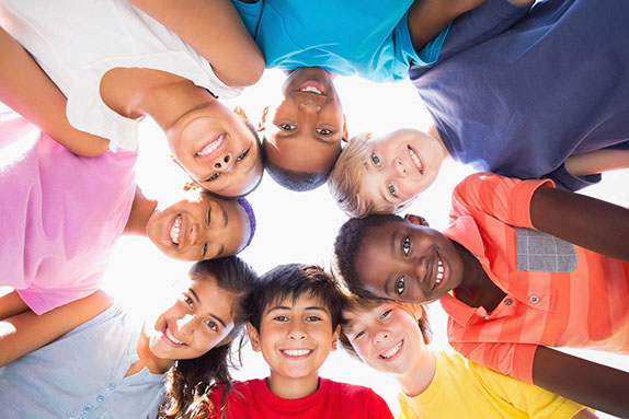 group of diverse kids standing in a circle looking down at camera