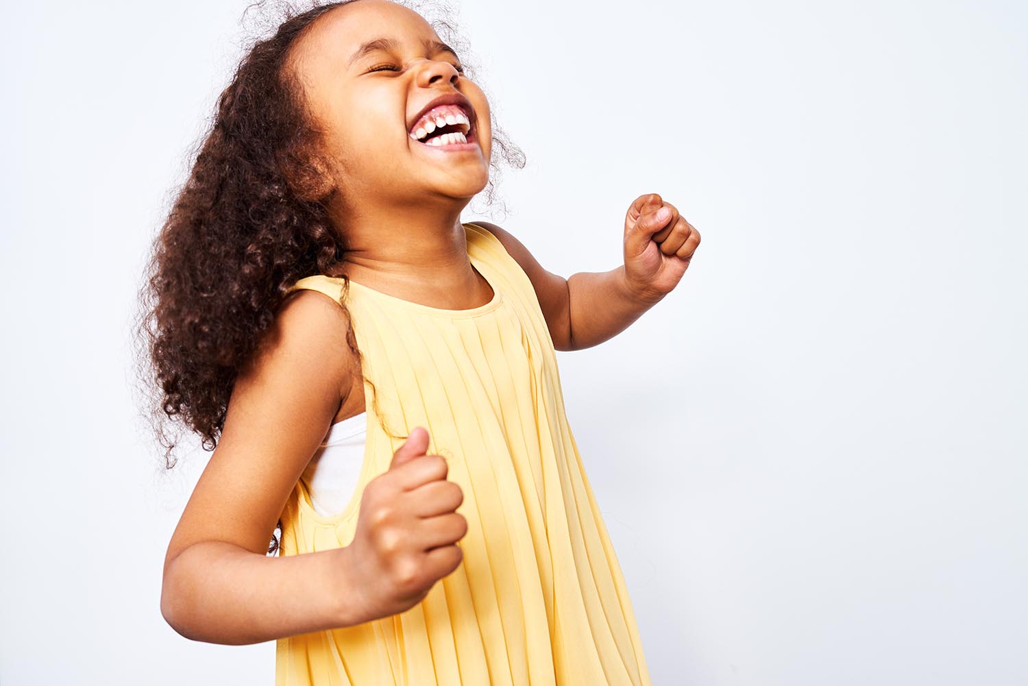 Girl smiling big with yellow dress on